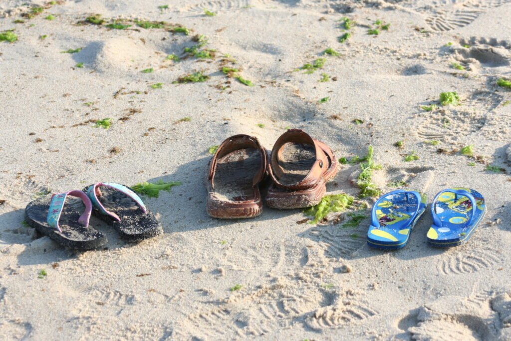 Three sets of sandals in the sand on Cape Cod