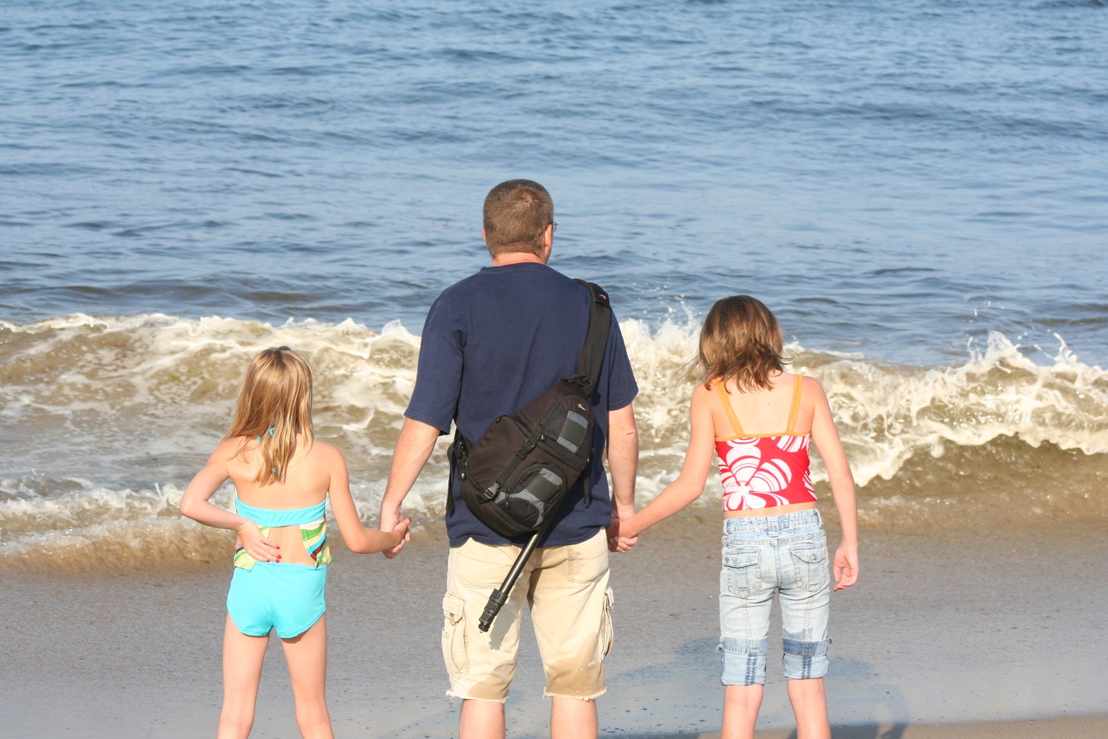 Adult and two children looking out into the atlantic waves
